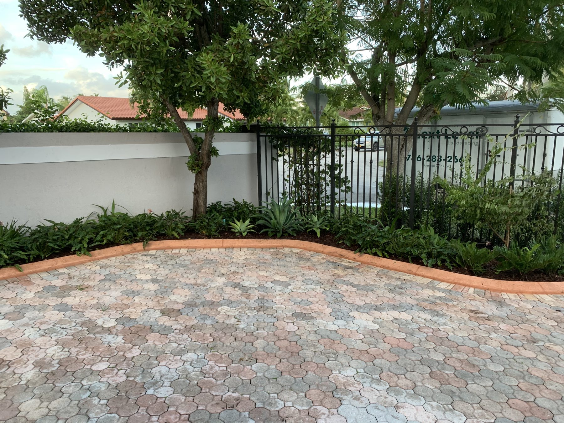 Paver drive with clipped hedge and garden wall